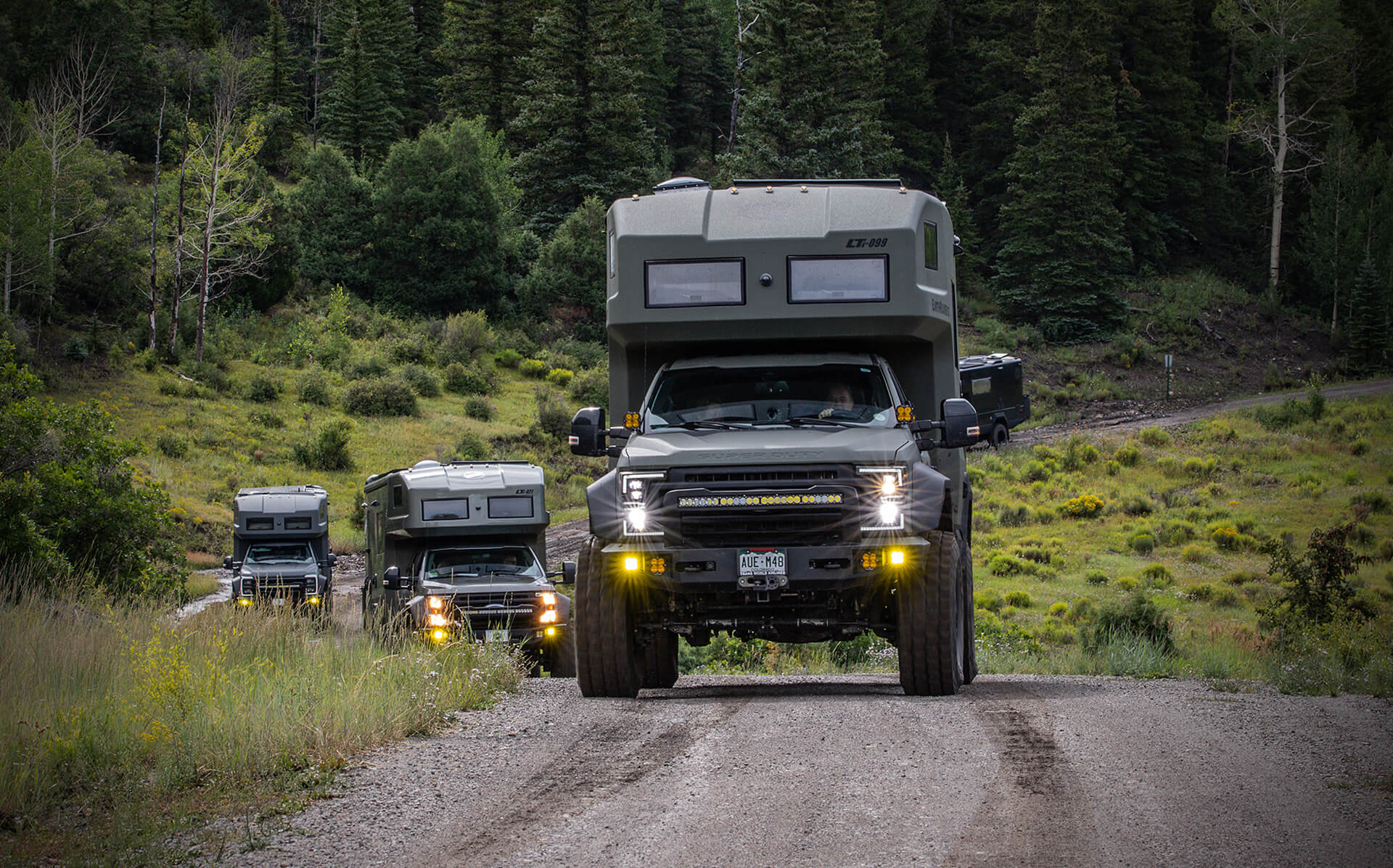 Group of EarthRoamer LTi vehicles driving through forest trail