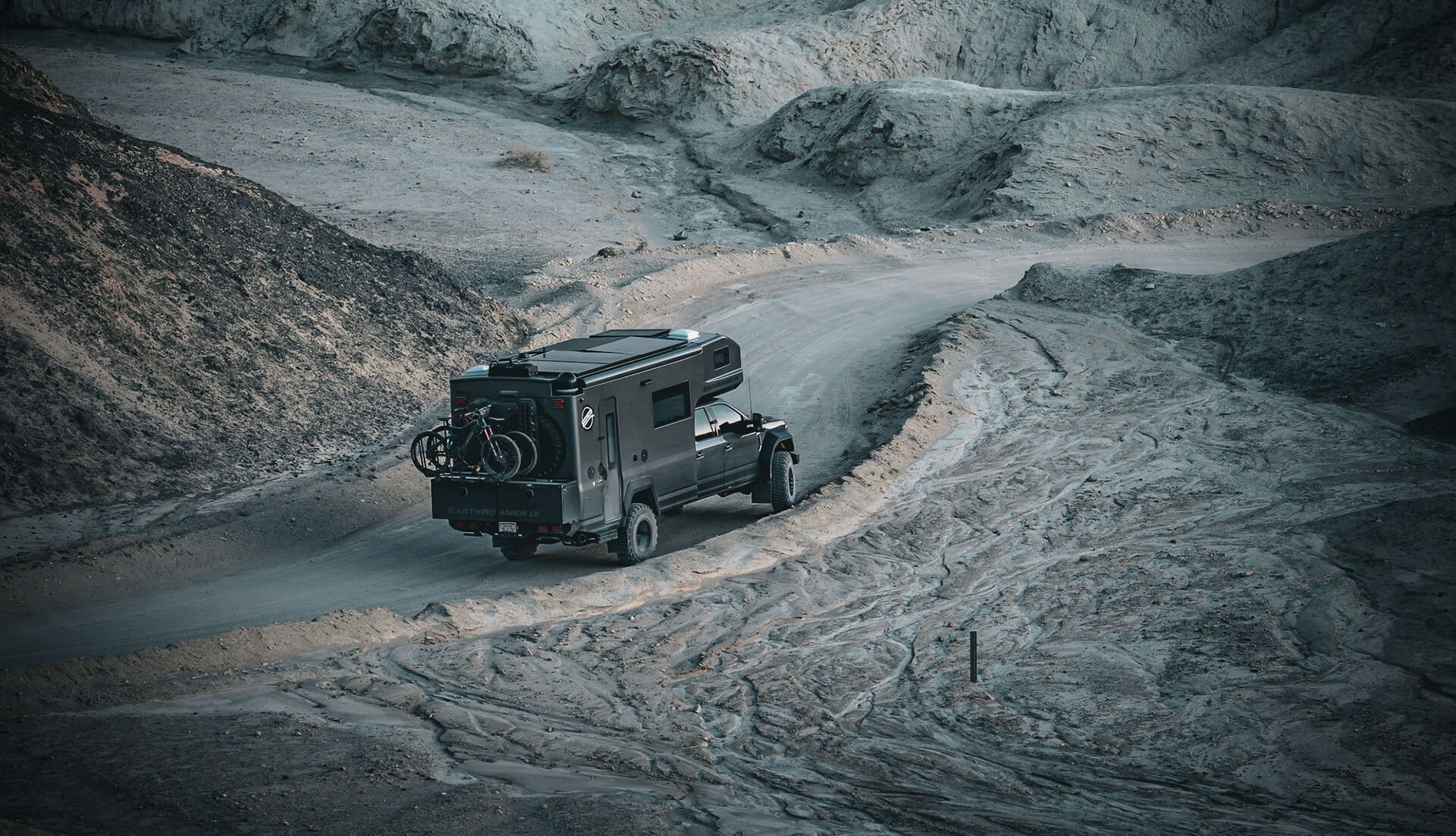 EarthRoamer SX off-road vehicle driving through rocky forest path