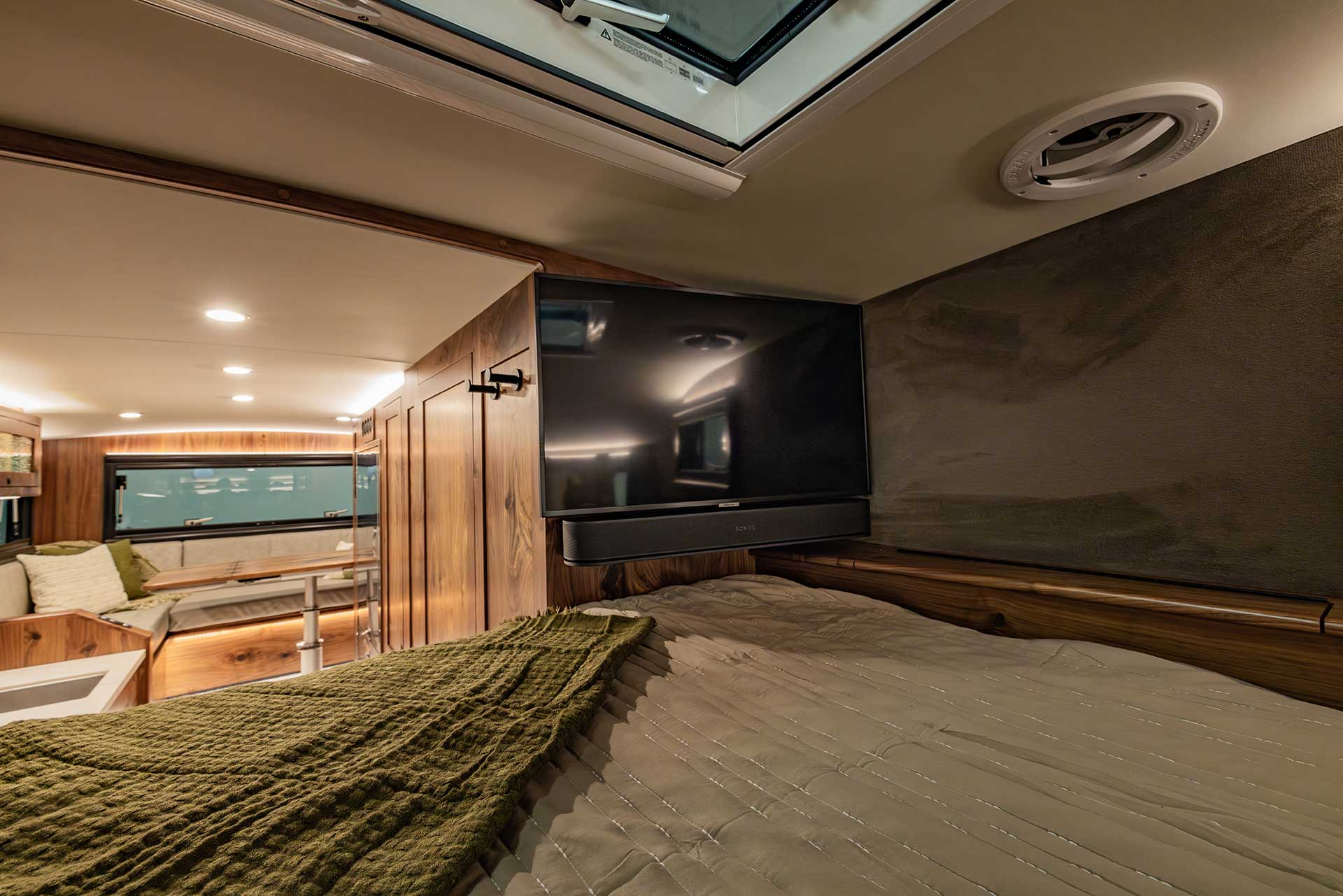 EarthRoamer bathroom interior with modern shower, wood-trimmed mirror, and small sink.