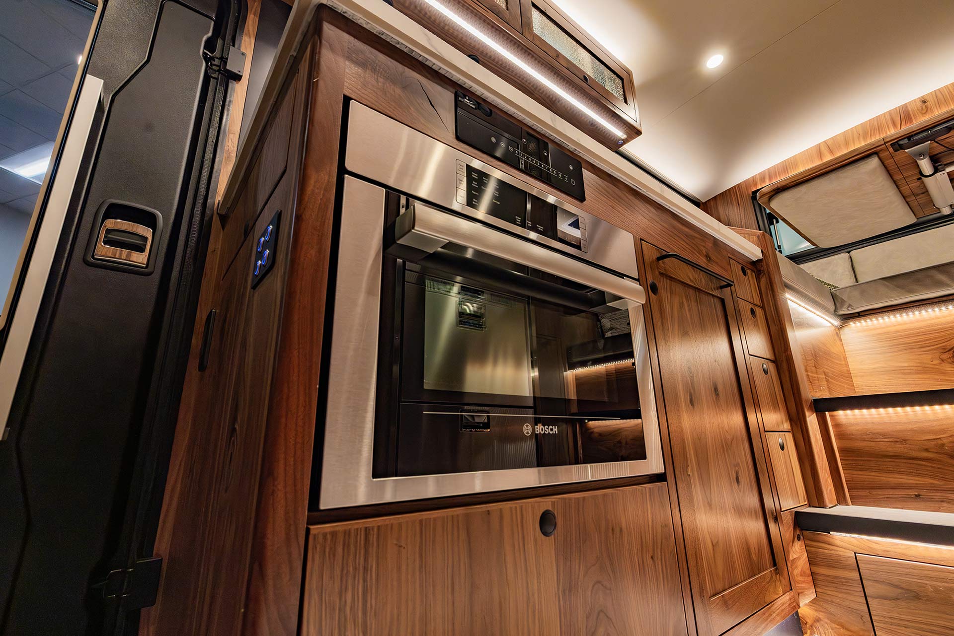 EarthRoamer kitchen with built-in Bosch oven surrounded by luxury wooden cabinetry.
