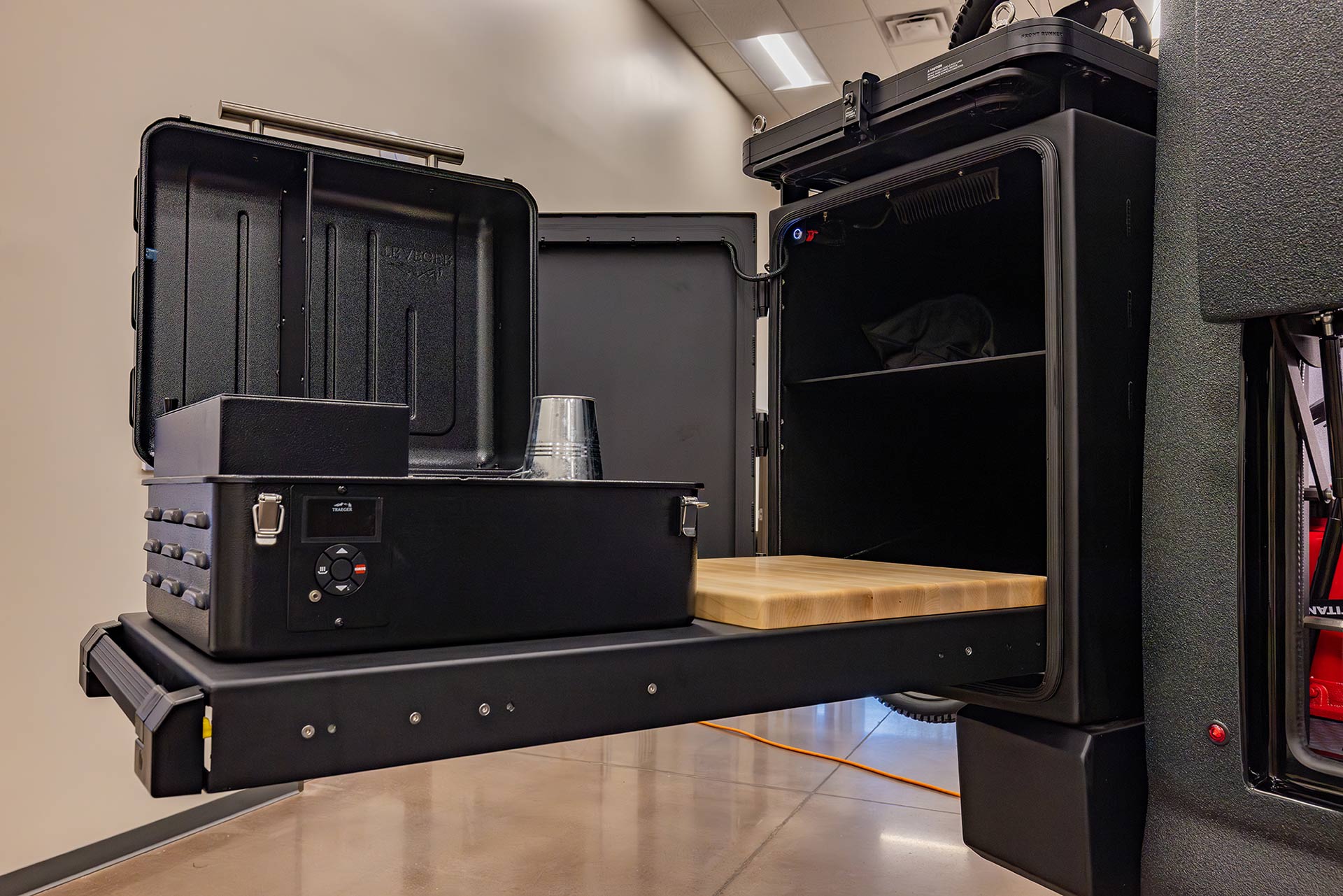 EarthRoamer exterior pull-out kitchen drawer with integrated grill and wooden prep surface.