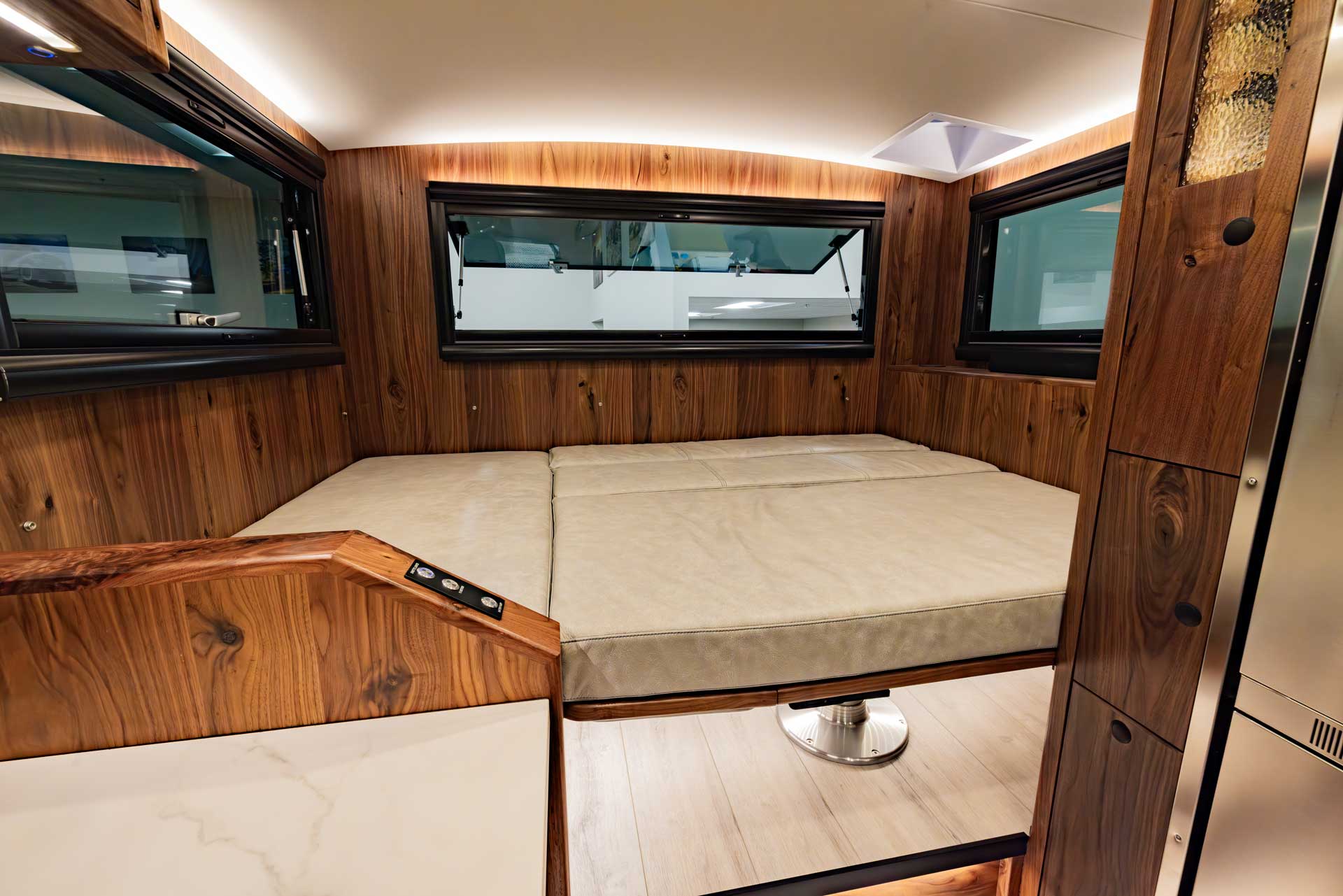 EarthRoamer LTi convertible lounge transforming into a full-size bed with wood-paneled walls.
