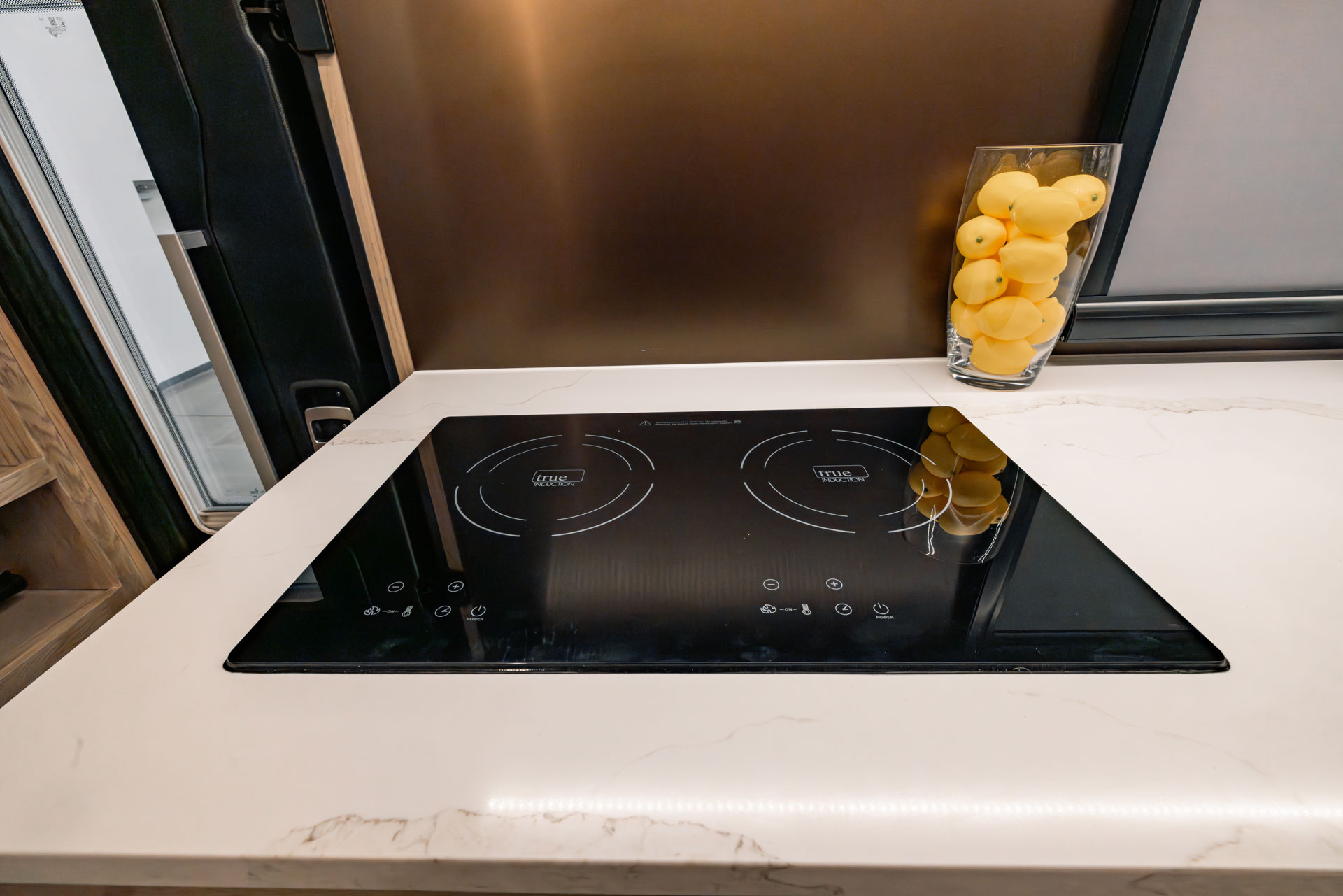 Modern induction cooktop on white marble counter inside EarthRoamer SX kitchen