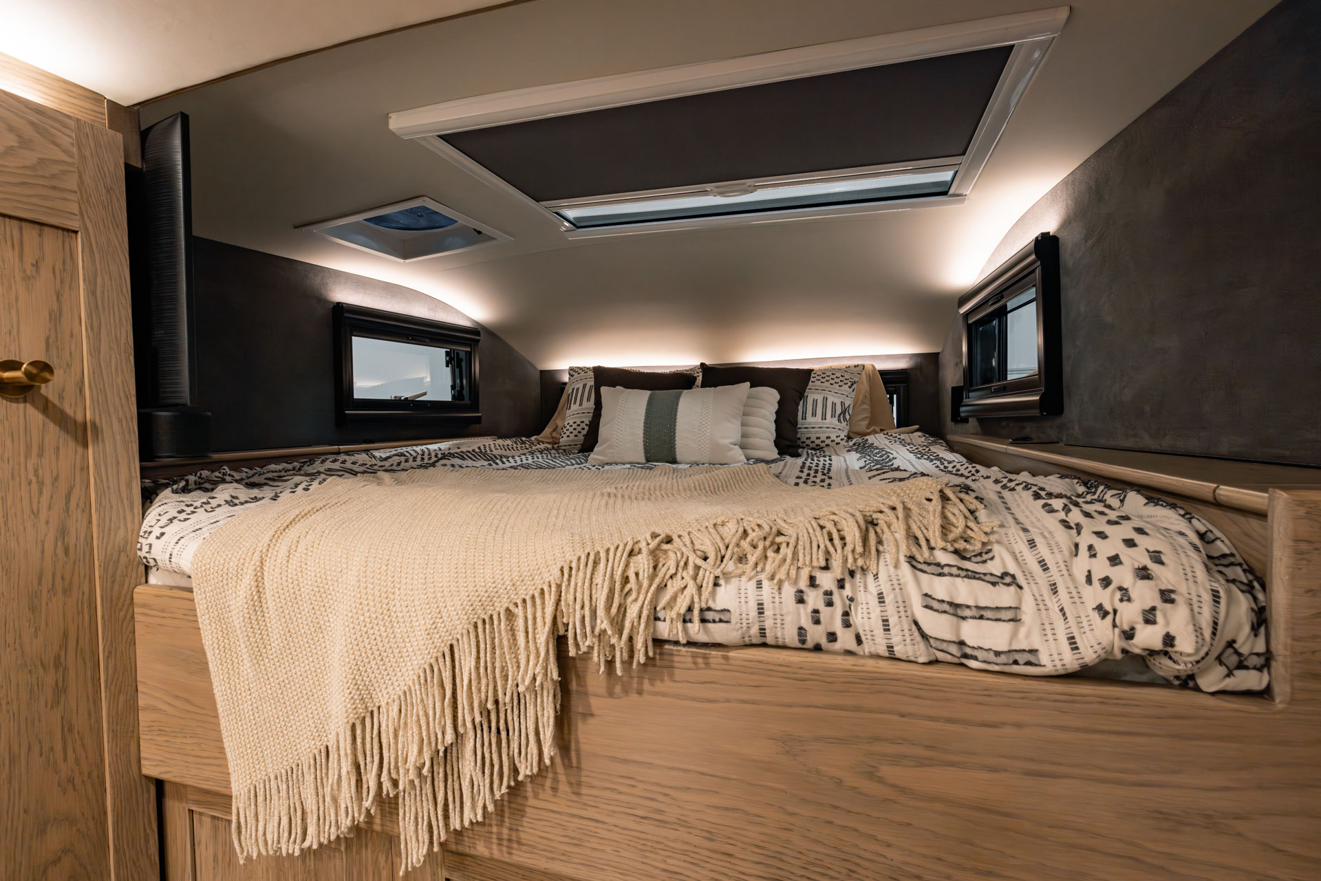 Cozy EarthRoamer SX bedroom with skylight, side windows, and decorative pillows