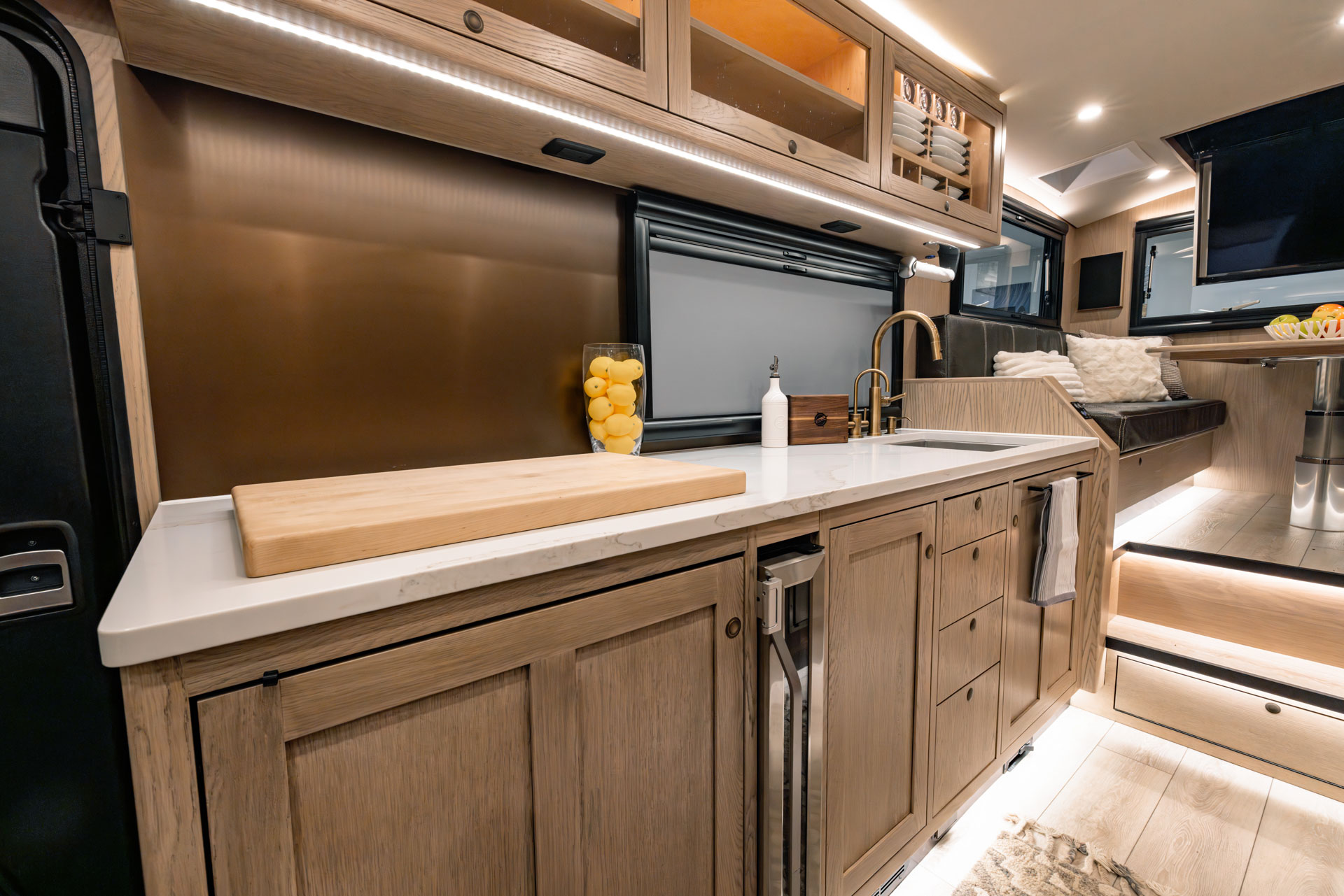 EarthRoamer SX kitchen view with sink, cutting board, induction cooktop, and lounge seating