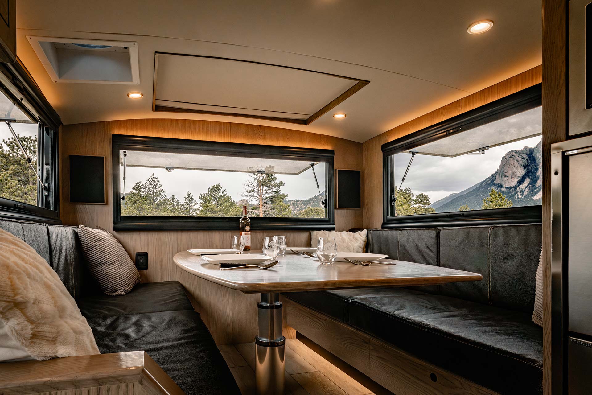 EarthRoamer SX dining area with wood table set for dinner and mountain view through large windows
