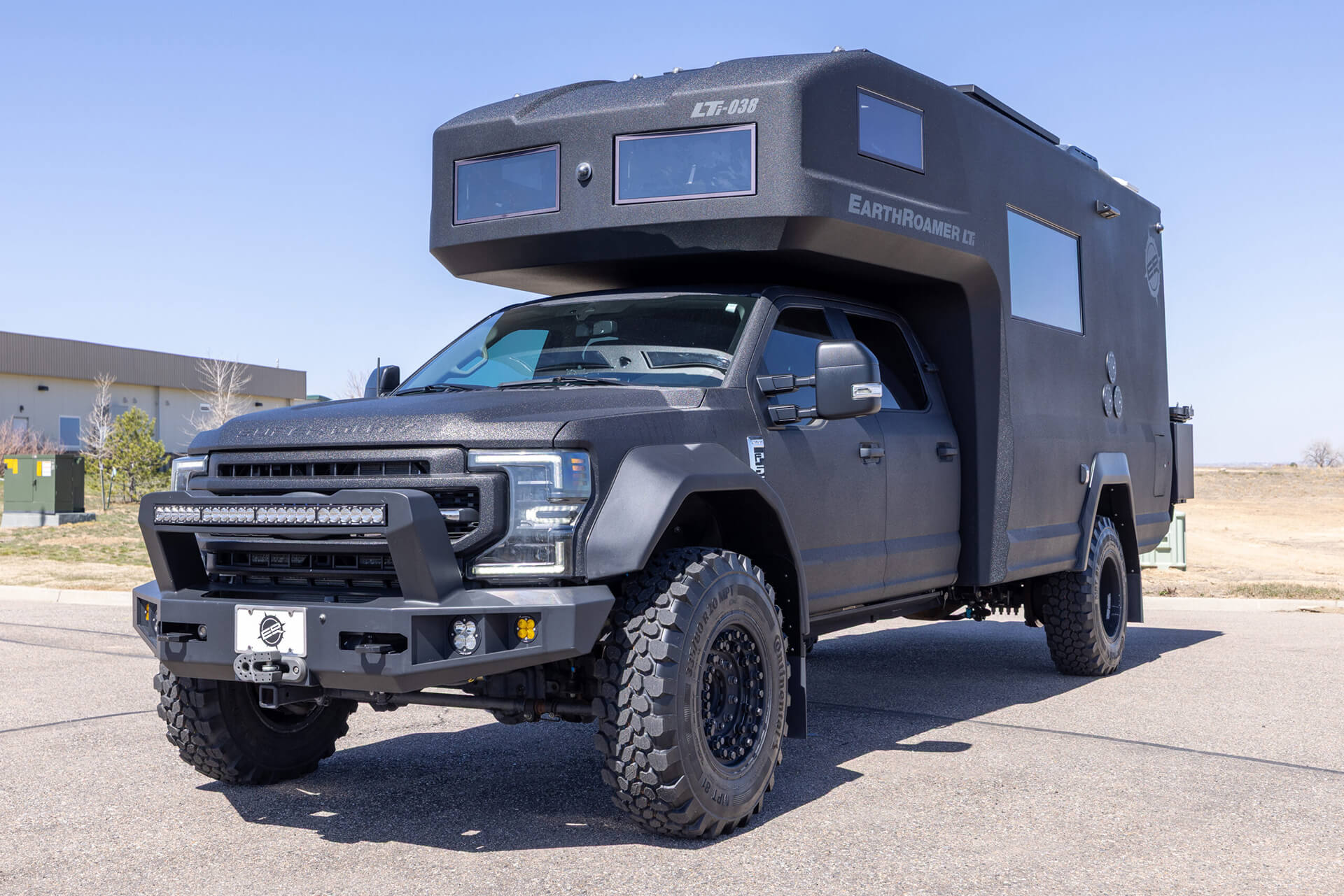 EarthRoamer camper bedroom with luxurious bedding, wood accents, and built-in lighting.